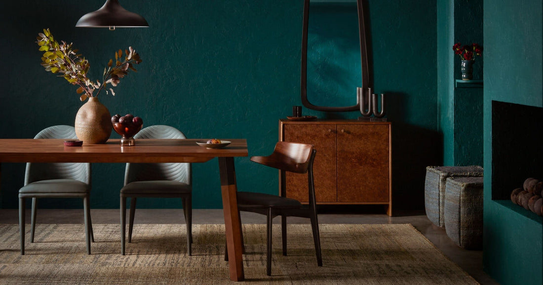 Elegant dining room with dark teal walls, modern wood furniture, and a textured area rug.