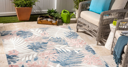Pastel tropical rug on a sunny patio with wicker chairs, plants, and a green watering can.