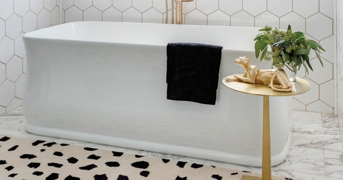 Elegant bathroom with a freestanding tub, gold fixtures, and a black-and-white patterned area rug.