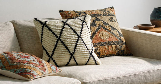 Traditional and modern decorative pillows on a gray couch. 