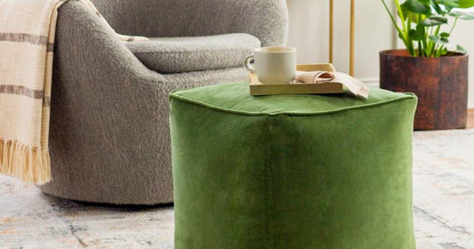 A modern living room with a plush green pouf, cozy chair, and decorative elements.