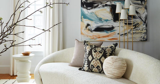 A modern fresh living room decor with a cream sofa, pillows, side table and floor lamps.