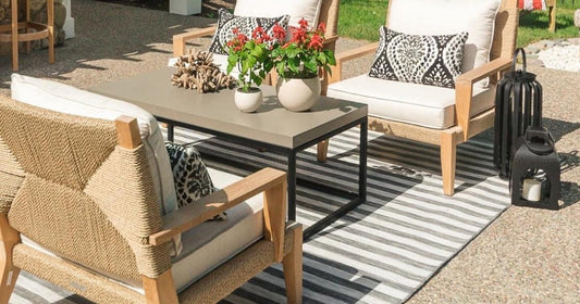 Outdoor seating with neutral chairs, striped rug, and potted plants on table.