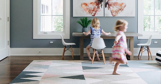 Children playing in a room with a colorful geometric rug and modern decor.