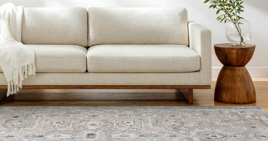 Neutral sofa with a light, patterned area rug and wooden side table, creating a calm aesthetic.