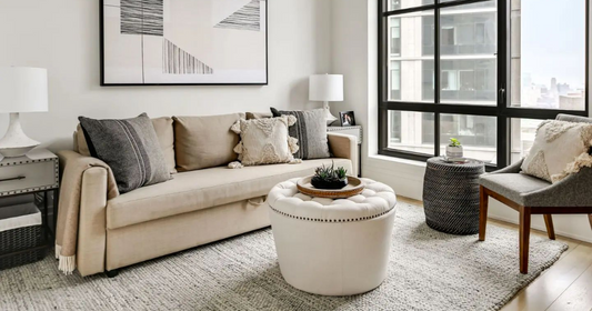 A small living room with a neutral decor and a beige area rug