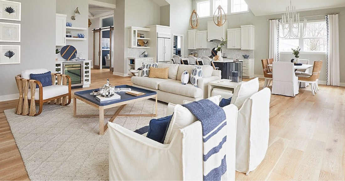 Coastal living room with white furniture, blue accents, and natural textures in an open-plan design.