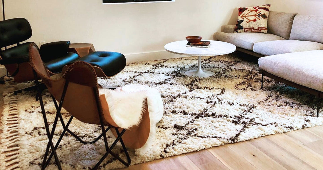 Living room with a beige sectional, black chairs, and a cozy shag rug featuring geometric patterns.