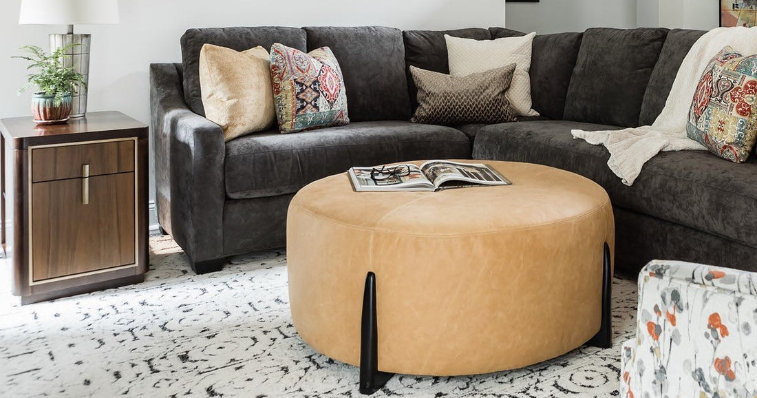 Living room with dark gray sectional, leather ottoman, and a patterned black and white area rug.