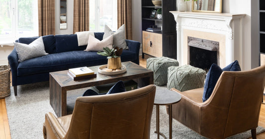 Living room with a navy velvet sofa, leather armchairs, a rustic coffee table, and a cozy fireplace.