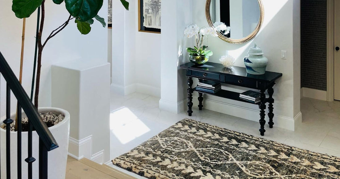 Elegant entryway with black console, round mirror, and Larrimore Global Black Area Rug.