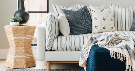 Living room scene featuring a cream and navy throw blanket on a striped sofa with accent pillows.