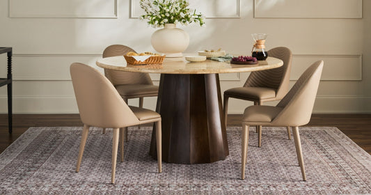 Elegant dining area with a round table, beige chairs, and a patterned rug for a cozy setup.