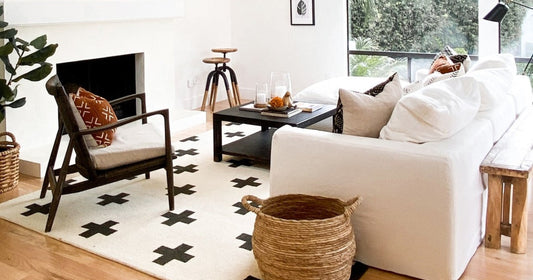 A cozy living room with a modern black & white rug featuring cross patterns, natural decor accents.