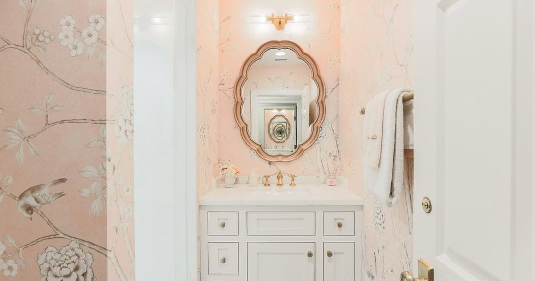 Elegant bathroom with a pink floral wallpaper and a decorative mirror above a white vanity cabinet.