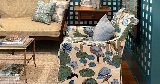 Living room with floral armchairs, artwork, and a cream rug on a textured blue wall.