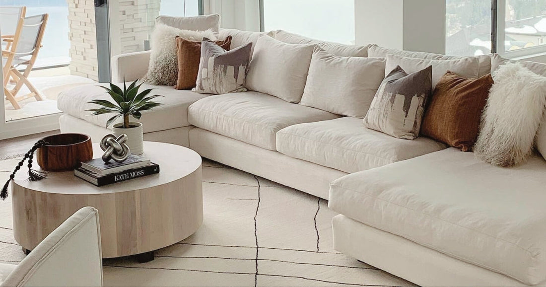 A living room with sectional sofa and a contemporary cream area rug with subtle black lines.